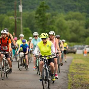 A group of riders on their bikes, wearing helmets, at the start of the ride