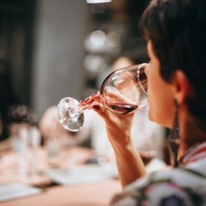 Woman tasting wine in stemmed glass