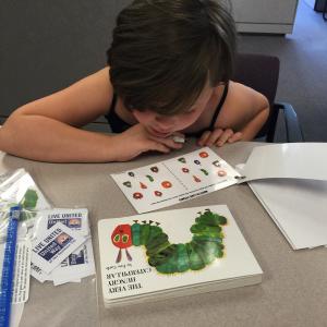 Youngster plays learning game with book "The Very Hungry Caterpillar."